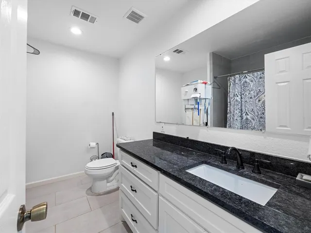 a bathroom with a granite countertop sink a toilet and a mirror