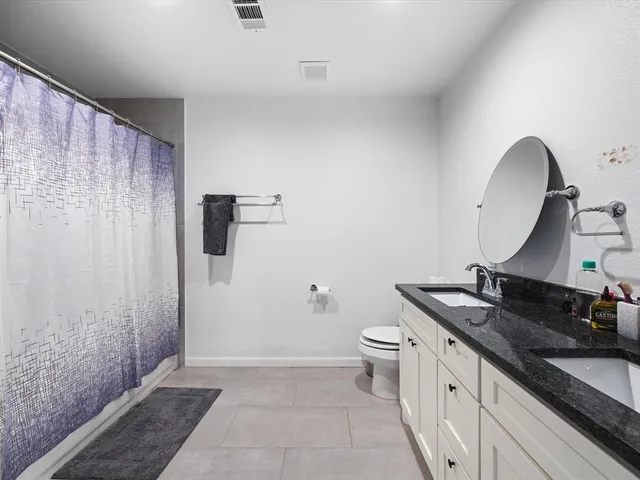 a bathroom with a granite countertop sink a toilet and shower