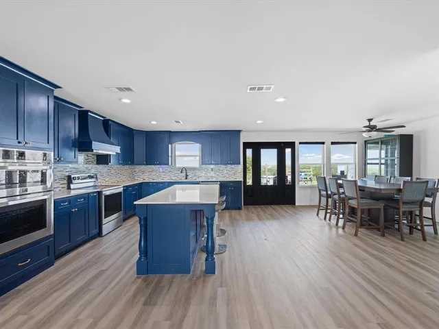 a kitchen with stainless steel appliances kitchen island wooden floors granite counter tops and white cabinets