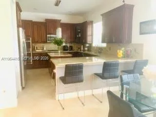 a kitchen with kitchen island granite countertop a stove top oven a sink a dining table and chairs