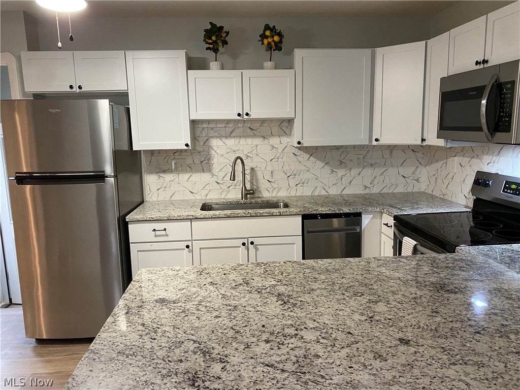 1547 Sunview Road Cleveland, OH 44124 - Photo 7 of 27 Kitchen with stainless steel appliances, light stone counters, and white cabinets