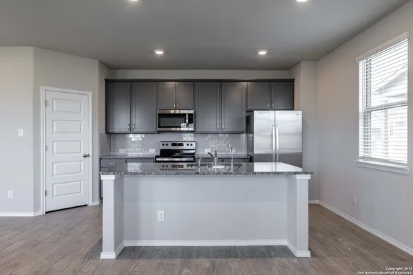a kitchen with stainless steel appliances a refrigerator a stove a sink and white cabinets
