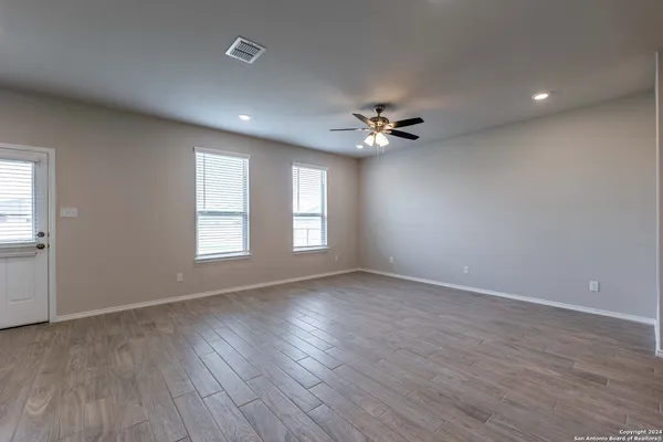 a view of an empty room with a window and wooden floor