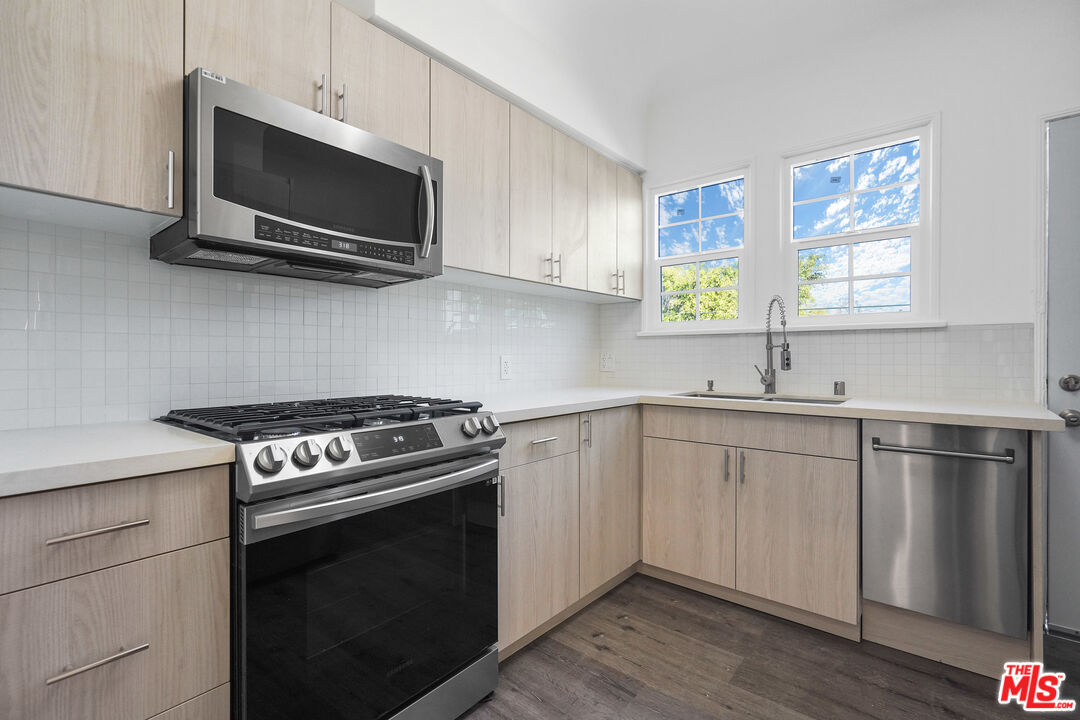 228 South Reeves Drive, Unit D Beverly Hills, CA 90212 - Photo 6 of 13 a kitchen with stainless steel appliances a sink a stove and microwave