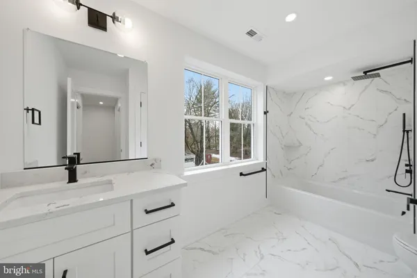 a bathroom with a tub sink and mirror