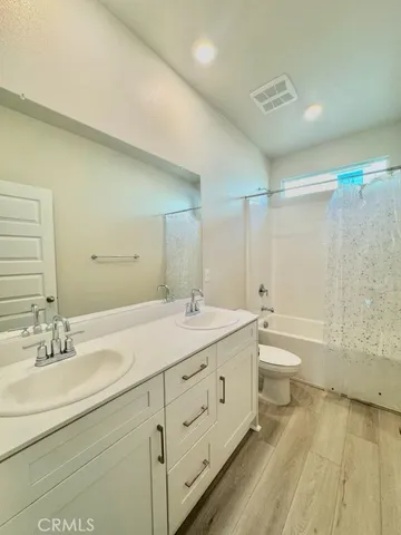 a spacious bathroom with a double vanity sink toilet mirror and bathtub