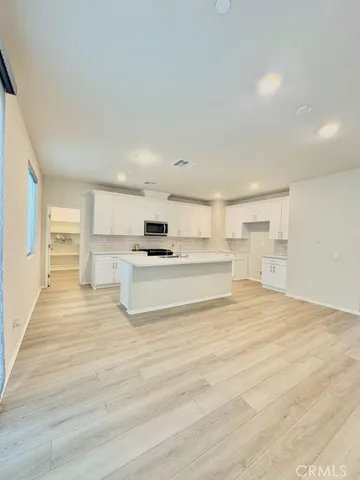 a view of kitchen with granite countertop white cabinets and refrigerator