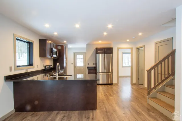 a kitchen with kitchen island granite countertop a sink a refrigerator and wooden floor