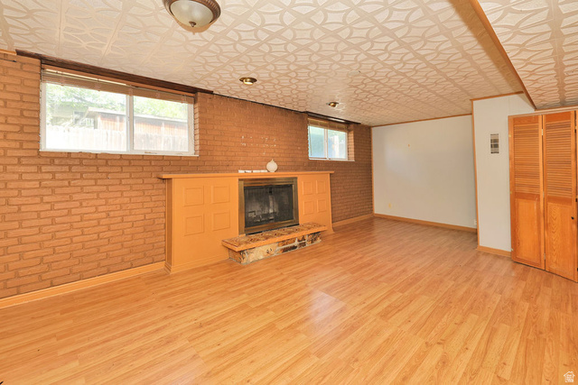 669 Colonial Avenue Layton, UT 84041 - Photo 28 of 51 Wood-finish flooring, brick accent wall, fireplace with stone hearth, built-in wooden cabinetry, and patterned ceiling panels
