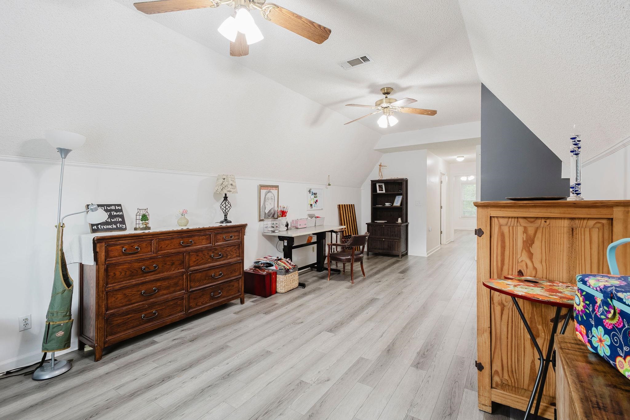 305 Great Falls Road Collierville, TN 38017 - Photo 14 of 23 Spacious room featuring vaulted ceilings, two ceiling fans, wood-finish flooring, and white painted walls with dark accent paneling