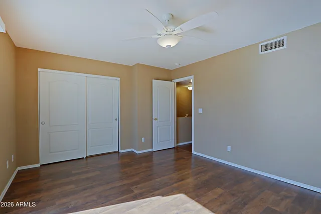 an empty room with wooden floor and ceiling fan