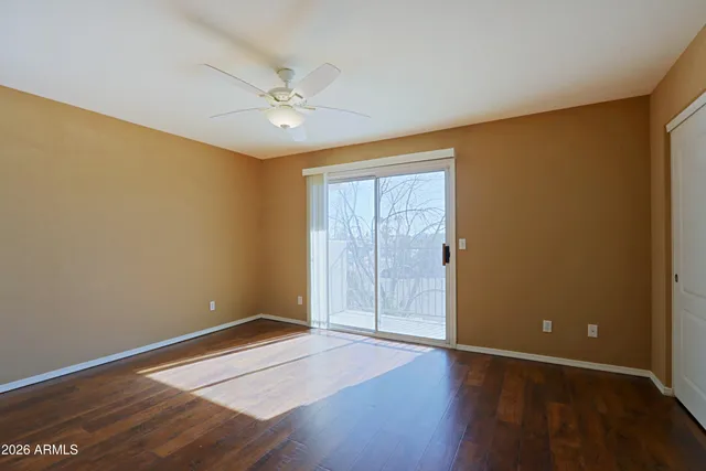 an empty room with wooden floor fan and windows