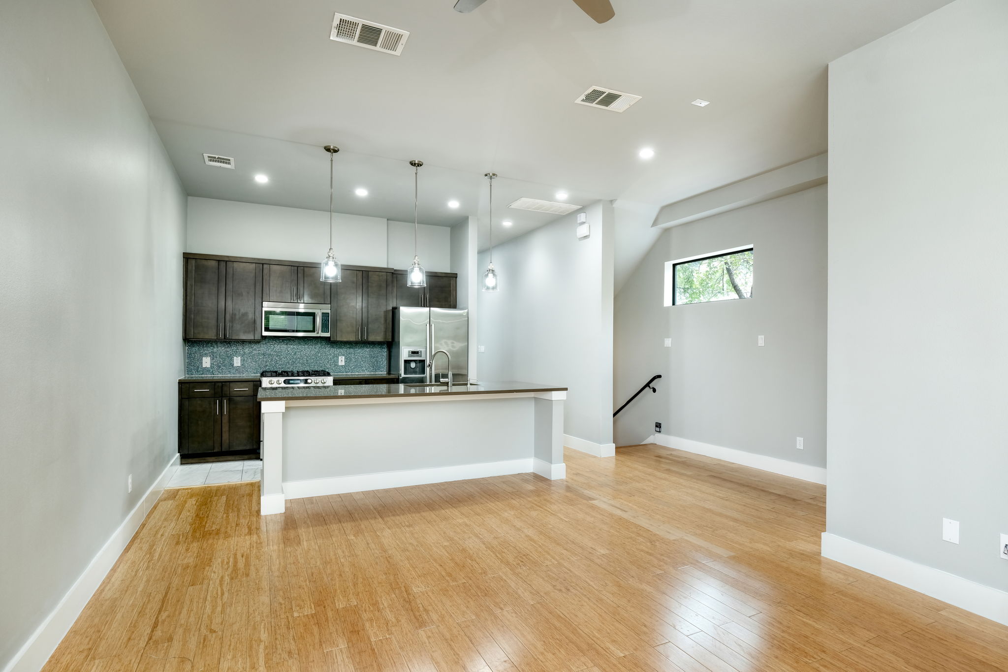 3000 Speedway Street, Unit E Austin, TX 78705 - Photo 1 of 16 A contemporary open-concept space features hardwood floors, recessed lighting, and a modern kitchen island with pendant lights.