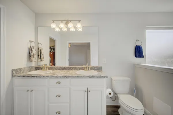 a bathroom with a granite countertop sink vanity mirror and toilet