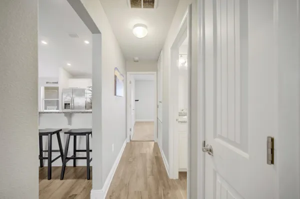 a view of a hallway with wooden floor and a bathroom