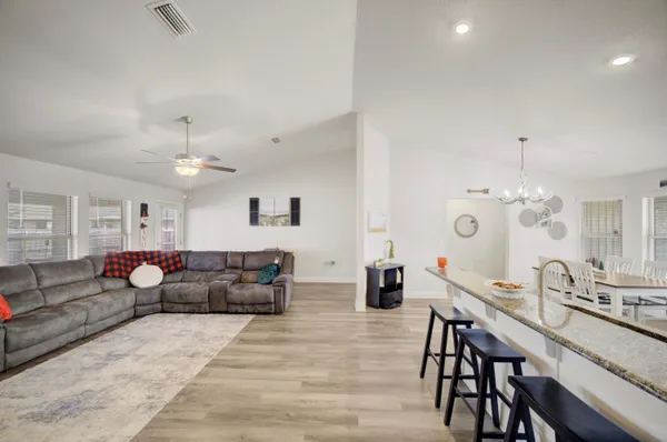 a living room with furniture kitchen view and a chandelier
