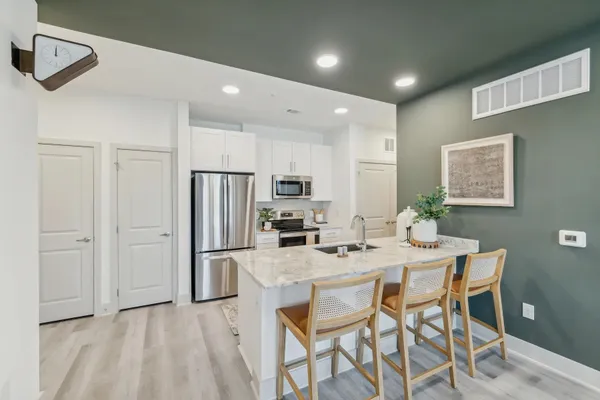 a kitchen with stainless steel appliances granite countertop a dining table chairs refrigerator and microwave