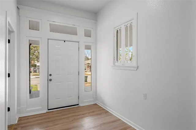 a view of an empty room with wooden floor and windows