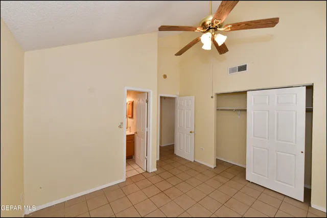 a view of an empty room with window and chandelier fan