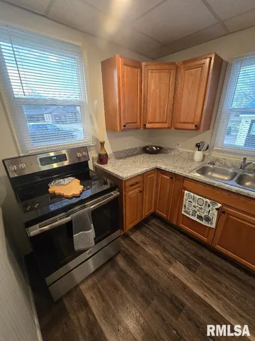 a kitchen with stainless steel appliances granite countertop a refrigerator a sink a stove a washer dryer and a window