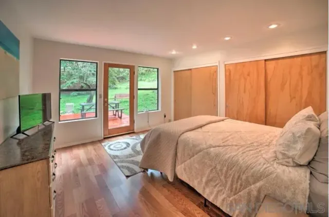 a spacious bedroom with a large bed and a large window with wooden floor