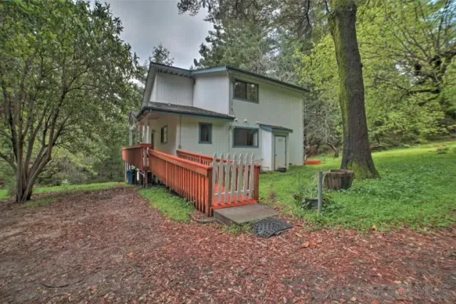 a view of a house with a yard and large trees
