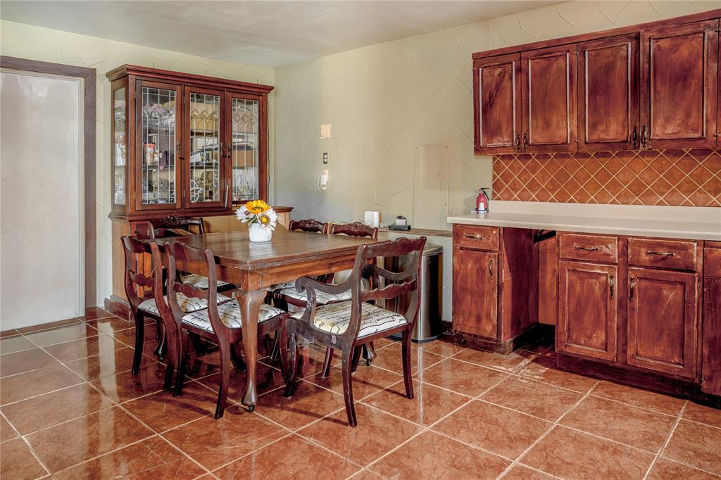 6317 Locust Street Rowlett, TX 75089 - Photo 10 of 34 Kitchen and dining area featuring rich wood cabinetry, extensive countertop space, a ceramic tile backsplash, and large square tile flooring