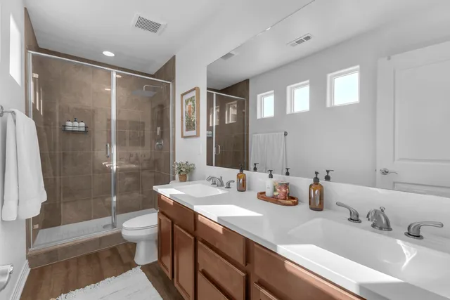 a bathroom with a double vanity sink toilet and shower