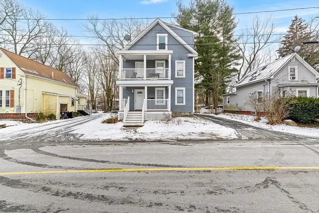 a white house that has a tree on the side of it