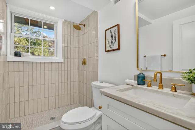 a bathroom with a granite countertop toilet a sink a mirror and a shower