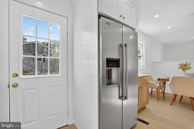 a kitchen with stainless steel appliances refrigerator stove microwave and chair