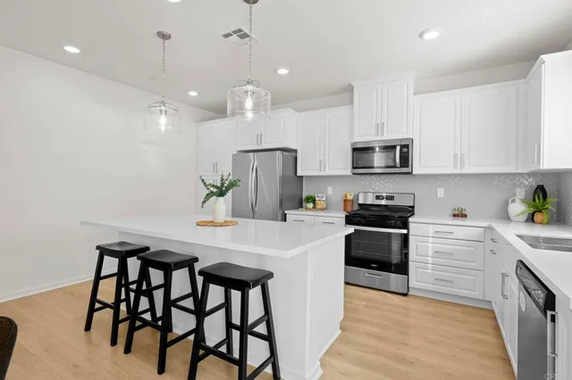 a kitchen with stainless steel appliances kitchen island a table chairs refrigerator and microwave