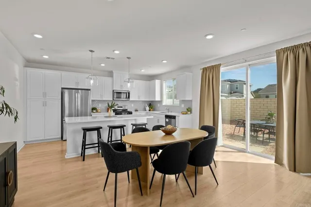 a kitchen with a dining table chairs and refrigerator