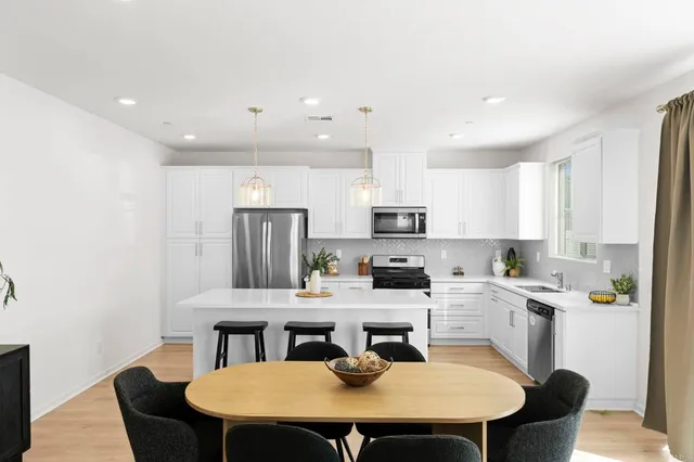 a kitchen with stainless steel appliances a kitchen island hardwood floor sink stove dining table and chairs