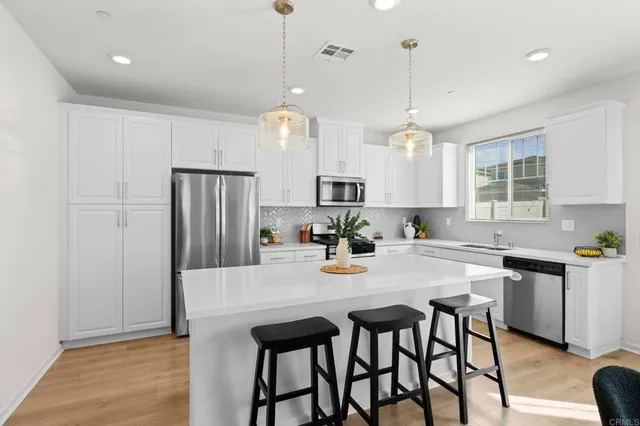 a kitchen with stainless steel appliances granite countertop a dining table chairs stove refrigerator and cabinets