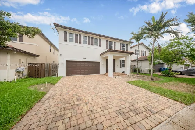 a front view of a house with a yard and potted plants