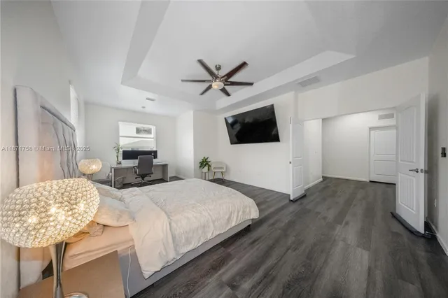 a spacious bedroom with a bed a mirror and a flat tv screen on dresser
