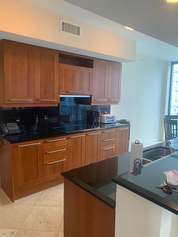 333 Las Olas Way, Unit 2803 Fort Lauderdale, FL 33301 - Photo 19 of 25 a kitchen with granite countertop a sink and a white cabinets