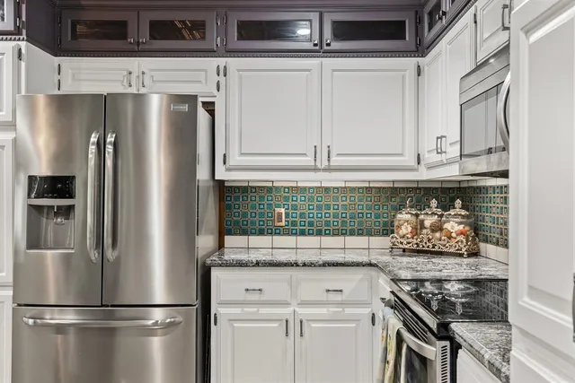 a kitchen with stainless steel appliances granite countertop a stove and white cabinets