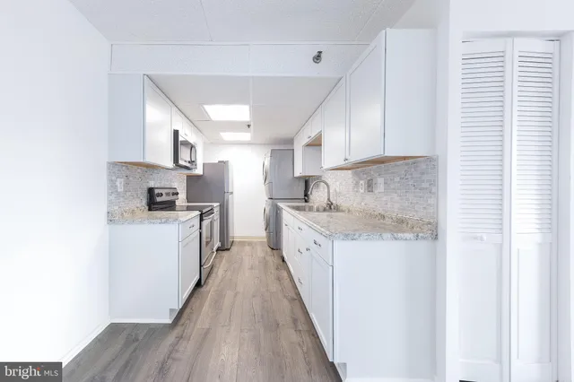 a kitchen with granite countertop a sink cabinets stainless steel appliances and a window