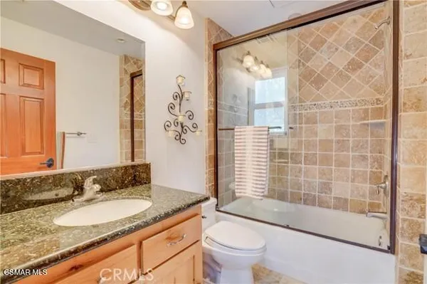 a bathroom with a granite countertop sink a toilet and shower