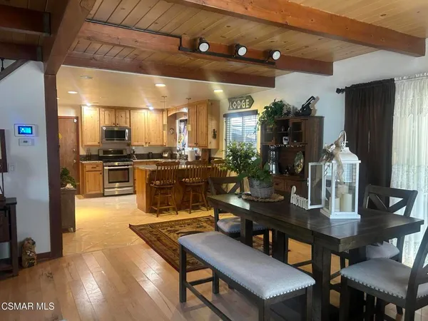 a kitchen with stainless steel appliances granite countertop a stove a refrigerator a kitchen island a dining table and chairs with wooden floor