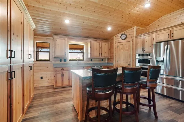 a kitchen with stainless steel appliances kitchen island granite countertop a table chairs and a refrigerator