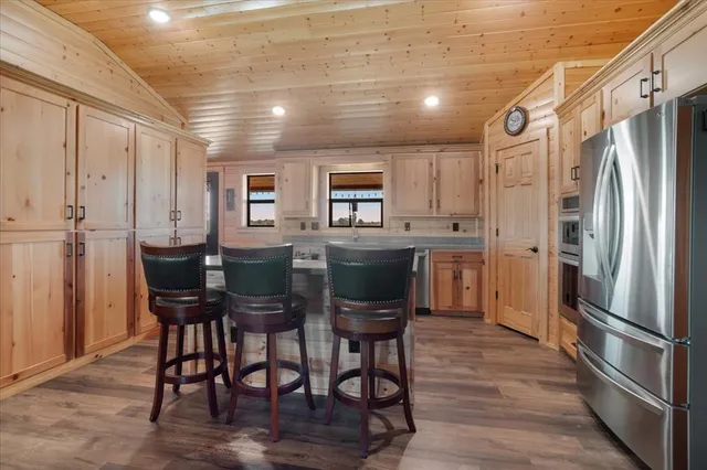 a kitchen with stainless steel appliances granite countertop a dining table chairs refrigerator and cabinets