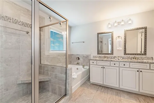 a bathroom with a double vanity sink mirror and bathtub