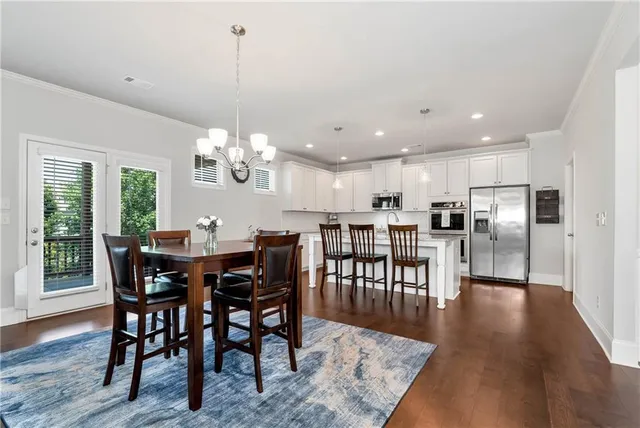 a view of a dining room and livingroom with furniture wooden floor a rug a chandelier