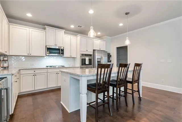 a large kitchen with stainless steel appliances granite countertop a stove a sink a dining table and chairs