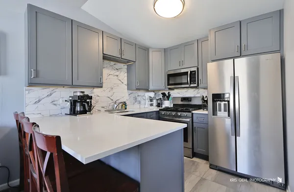 a kitchen with a refrigerator a stove a sink and white cabinets