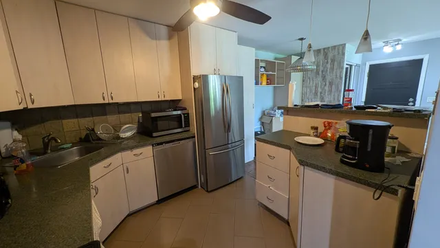 a kitchen with stainless steel appliances granite countertop a refrigerator a stove and a sink
