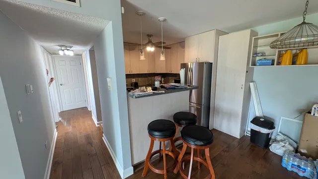a kitchen with stainless steel appliances granite countertop a refrigerator a stove a microwave oven a dining table and chairs with wooden floor